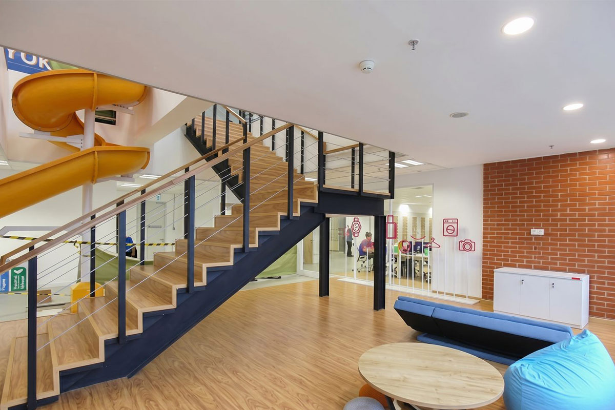 Lazada — upper floor communal area with orange chairs and slide exit